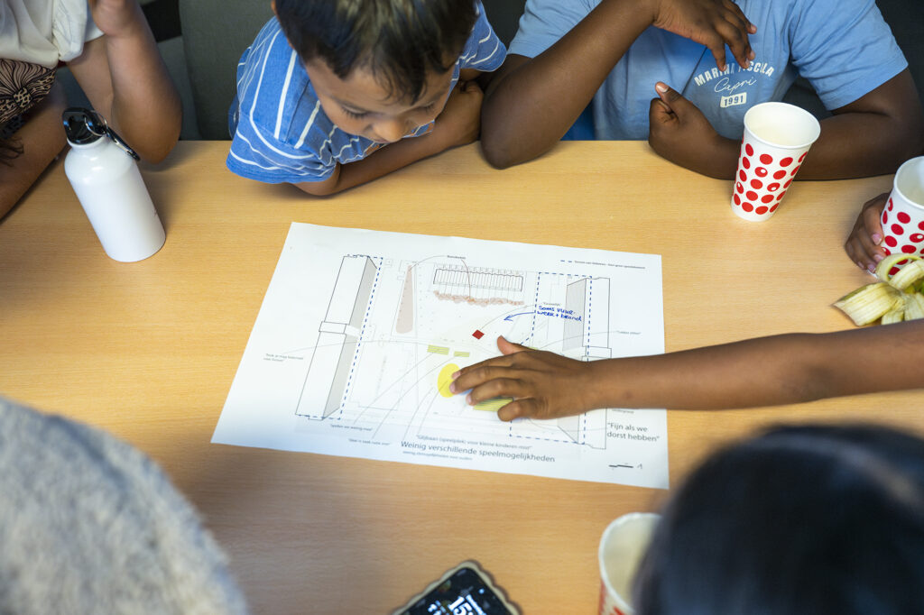 Jonge inwoners van de Debussyflat werken aan het ontwerp van de speeltuin.