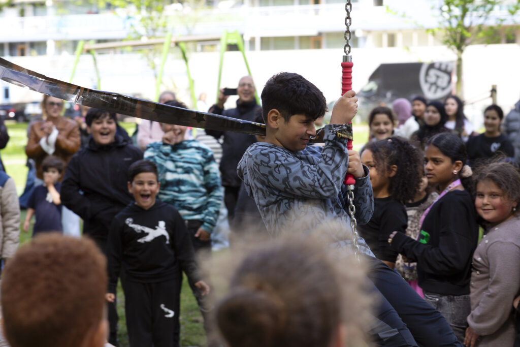 Een 11 jarige-jongen zit op een kabelbaan, omringd door kinderen.